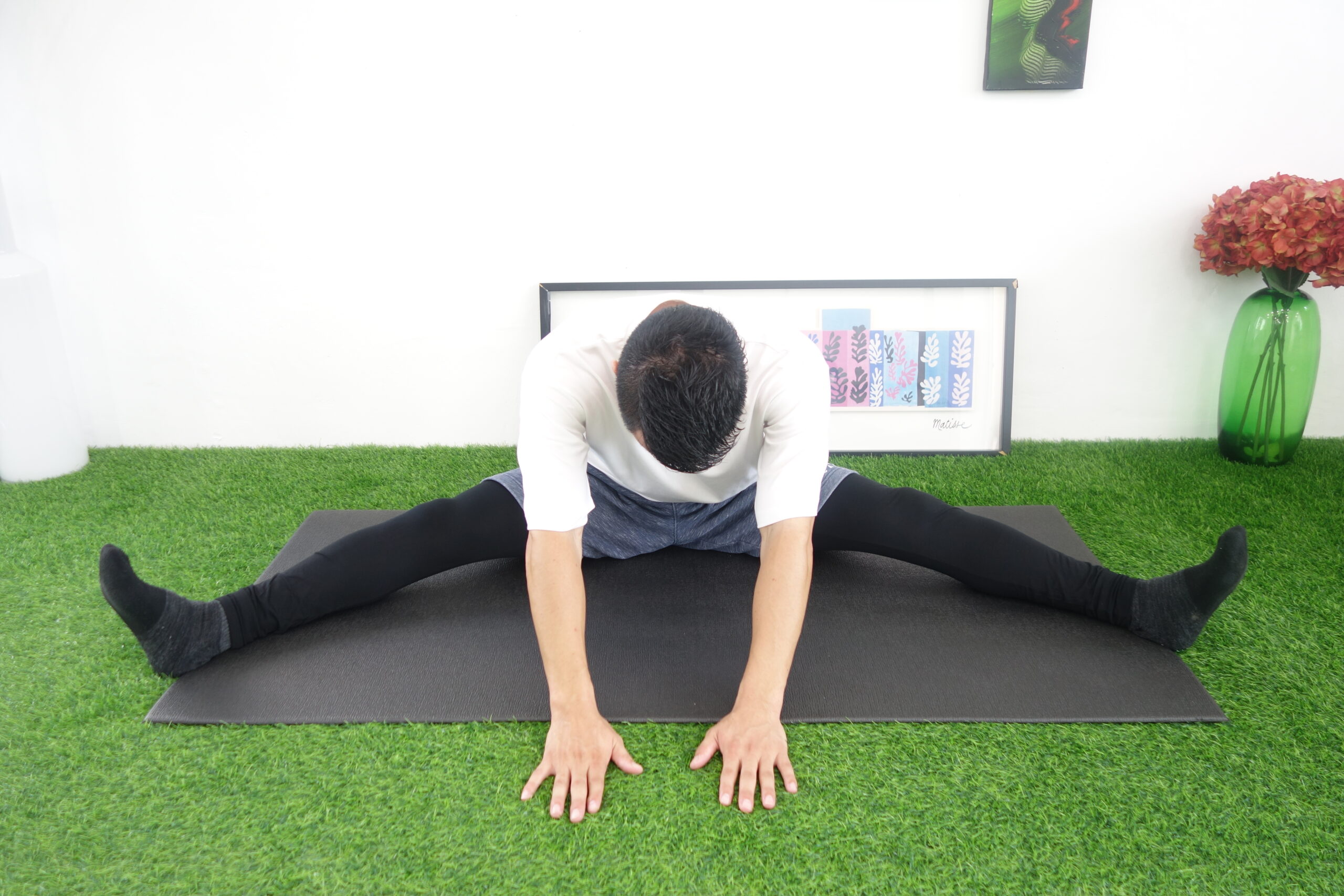 脚を伸ばした状態で先ほどよりもさらに開脚して前屈する